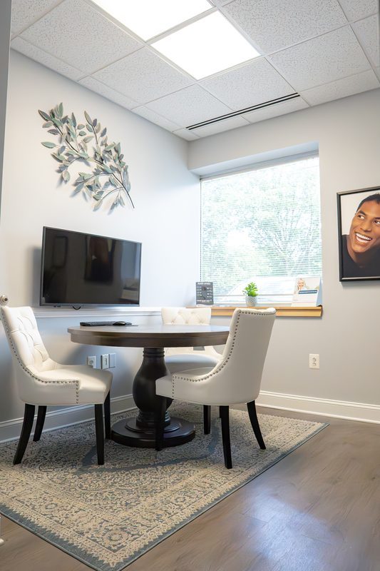 A quiet consultation room with a round table and upholstered chairs, where Dr. Arpan Patel meets patients before any treatment begins.